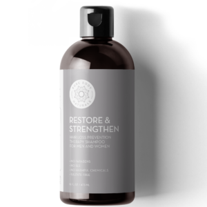 A bottle of Restore & Strengthen Shampoo for Hair Growth. The shampoo is designed for hair loss prevention and is free of parabens, SLS, harmful chemicals, and sulfates. The bottle is brown with a black cap and gray label.