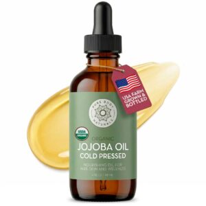 Bottle of organic jojoba oil with USA farm-grown tag and golden oil texture in the background.