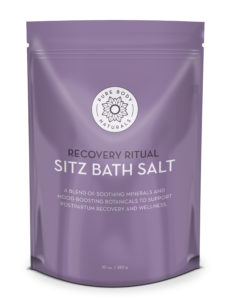 A purple resealable bag labeled "Pure Body Naturals" contains "Recovery Ritual Sitz Bath Salt, 10 oz." The text states it is a blend of soothing minerals and mood-boosting botanicals to support postpartum recovery and wellness. The bag weighs 10 oz (283 g).