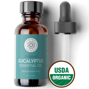 A brown glass bottle labeled "Organic Eucalyptus Oil, 1 fl oz" with 1 fl oz (30 ml) capacity is shown. The label is green with white text and a floral logo. A black dropper lies beside the bottle. A USDA Organic seal is displayed in the corner.
