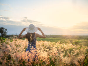 womanin sun dress in fields of flowers in sunlight